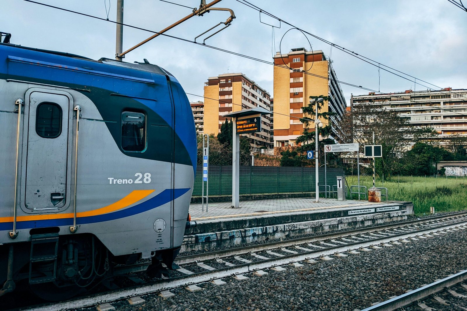 Train at a station in Rome, Italy with residential buildings in the background. Urban transport scene.