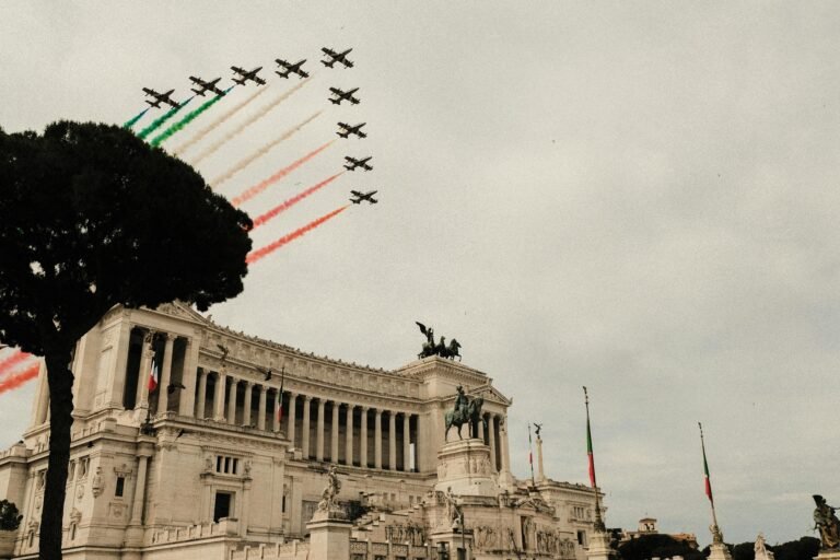 Low angle of air show over Victor Emmanuel Monument with sculptures and colonnade during National Unity and Armed Forces Day in Italy